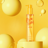 Bright yellow promotional image of A’pieu Pore King Minji Cleansing Oil, featuring the transparent golden bottle with pump surrounded by floating yellow spheres on a matching yellow background, highlighting a fresh and vibrant aesthetic.